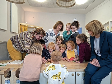 Die First Lady beobachtet und interagiert mit Kindern im Fröbel Kindergarten bei einer Sprachförderungsaktivität, bei der Bücher und Lernmaterialien verwendet werden.